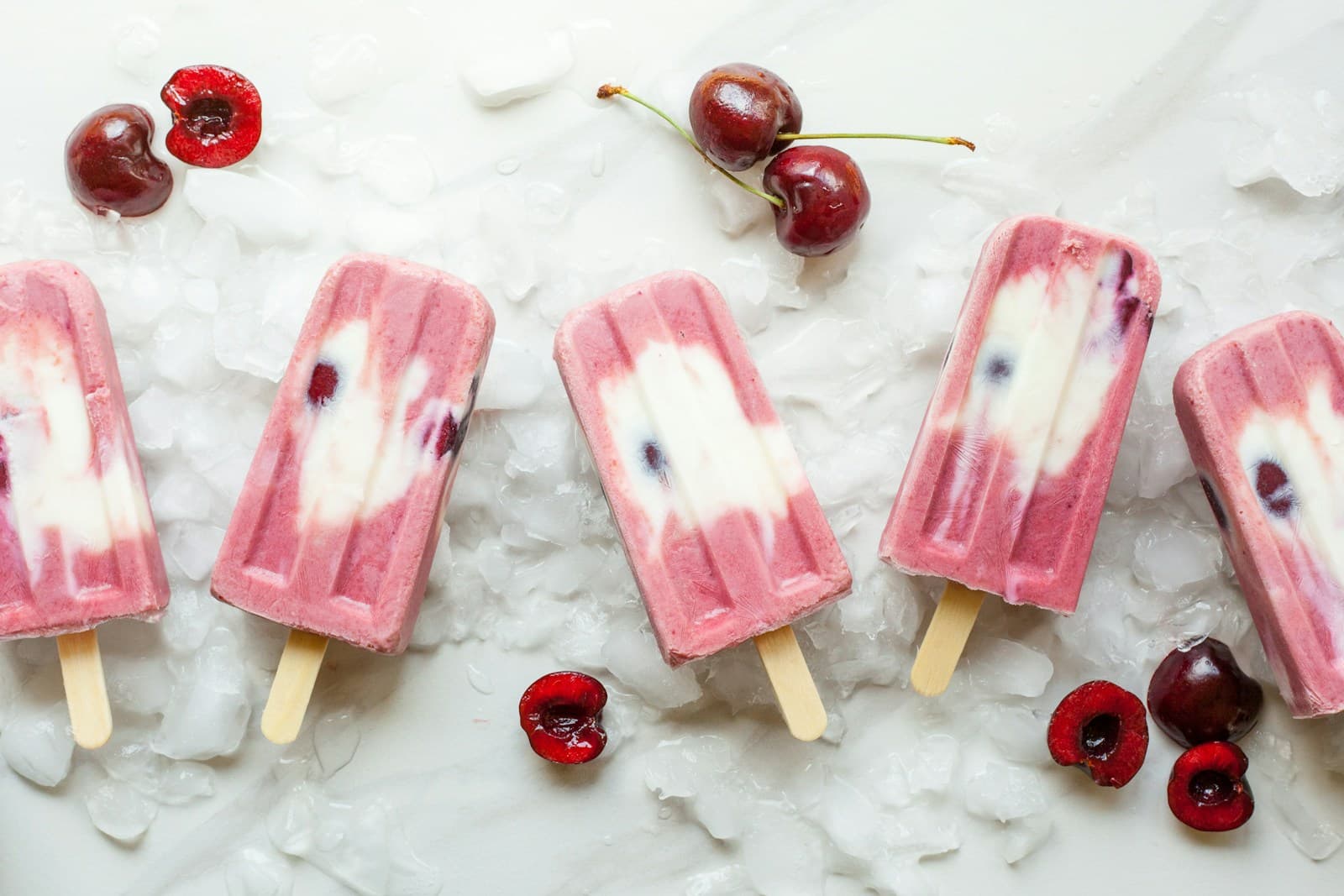 Paletas de fruta y cerezas sobre una superficie clara